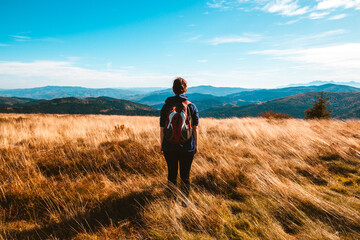 Alone girl with backpack,stands against a panorama of autumn mountains, the concept of traveling alone