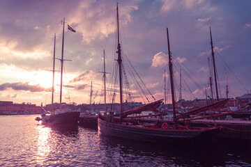 Wooden sailing boats at the city pier against a surreal purple sky