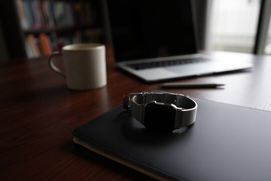 Work space home office dark wood desk with laptop coffee mug and smart watch business accessories workspace computer notebook 150chr - Powered by Adobe