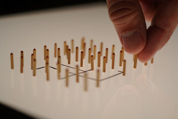 Hand Arranging Wooden Sticks on White Surface Conceptual Pattern Minimalist Still Life Creative Geometric Composition