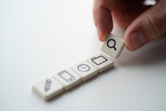 Human Finger Placing Search Icon Square Next to Digital Icons on White Tabletop Symbolizing Modern Data and File Retrieval - Powered by Adobe