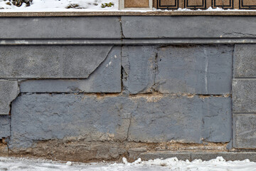 A concrete wall with snow on the ground next to it