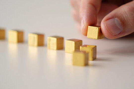 Close Up of Finger Touching Gold Cube in Row of Cubes Metallic Gold Material Square Shapes Minimalistic Concept of Finance Treasure