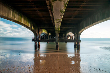 Extremely long exposure shot of the piles under Bournemouth Pier looking up.  Waves stilled and peaceful.