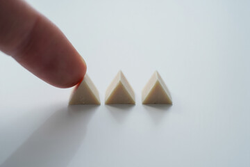 Index Finger Touching Small White Pyramid Block on White Surface Close Up 150 Characters