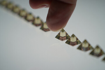 Hand Arranging Golden Triangular Prisms in Linear Fashion Illustrating Progression Strategic Planning and Organizational Structure