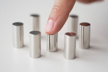Finger Touching Silver Metal Cylinder Displayed on White Surface Minimal Still Life Concept Modern Elegant Simplicity Contemporary Artistic