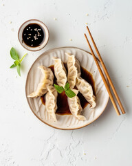 Clean flatlay of Chinese dumplings with soy sauce and ginger on white background