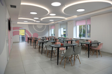Tables with chairs in stylish room at school