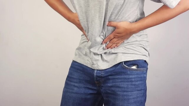 Stomach cramps, stomach aches, and other stomach ailments. A man's hands wrapped around his stomach indicate unbearable pain and injury in the abdominal area. Holding in a bowel movement.
