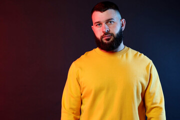 Obraz premium Portrait of handsome man on dark background with color lights. Space for text