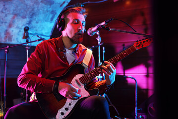 Man in headphones playing electric guitar on stage