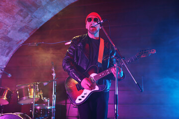 Obraz premium Man playing electric guitar on stage with smoke, low angle view