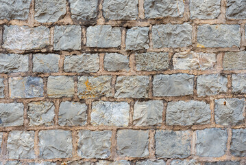 Close-up view reveals the intricate pattern and texture of aged stone bricks in a weathered wall. This building showcases craftsmanship from a bygone era, emphasizing durability and history