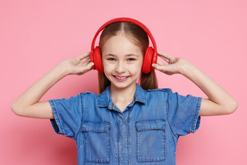 Cute girl in headphones on pink background