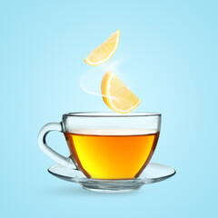 Citrus drink for health boosting. Lemon pieces falling into cup on light blue background. Cold season remedy