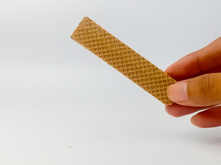 Hand holding chocolate wafer isolated on white background.