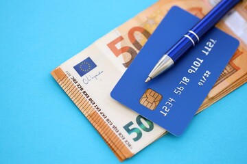 Credit card and pen with euro currency money bills banknotes on light blue background. Business, financial operations and accounting in European Union