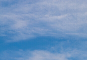 Blue sky filled with scattered white clouds. Fluffy cirrus clouds in summer day. Nature cloudscape background.