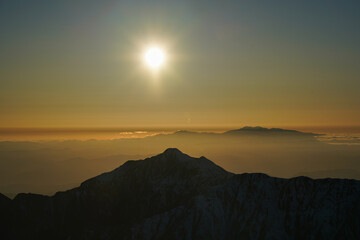 初冬の槍ヶ岳山頂から見る夕陽と笠ヶ岳