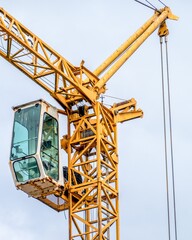 Yellow tower crane cabin with cloudy sky background
