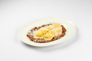 Plate of ravioli served with rich meat sauce and grated cheese topping on a bright white background