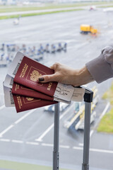 Russia. Saint Petersburg. Passenger holds airline tickets and a Russian passport against the background of the runway.