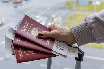 Russia. Saint Petersburg. Passenger holds airline tickets and a Russian passport against the background of the runway.