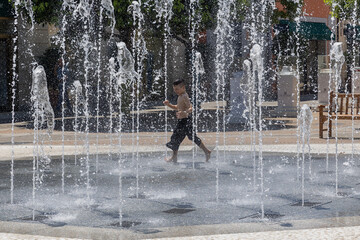 Italy. Caserta. A boy plays in water at a fountain square.
