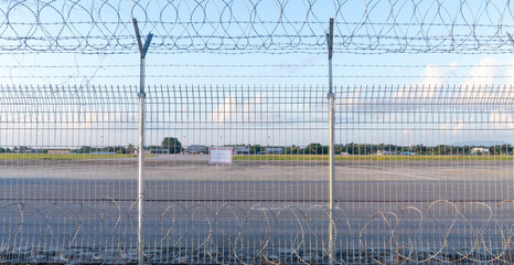 Barbed wire fence or wall located around forbidden area or zone of airfield at the airport