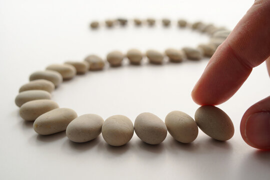 Finger About to Touch a Pebble Stone Placed in a Row on White Background, Represents Balance and Harmony with Selective Focus 150 - Powered by Adobe
