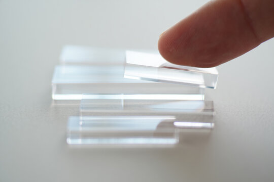 Clear Acrylic Blocks being Arranged by Finger on Light Background Indicating Transparency for Construction or Design Concept as Demonstration