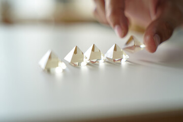 Hand Placing Crystal Pyramids in Graduated Row Demonstrating Order Progression Development Growth Increment Sequencing Stacking Arrangement