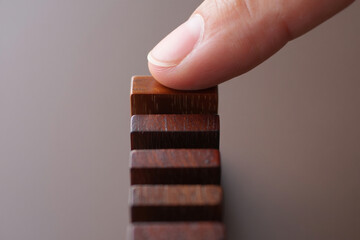 Human Finger Pushing Over Top of Dominoes Game Blocks Business Strategy Thinking and Step by Step Planning With Wooden Tiles