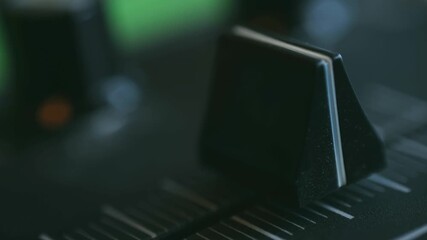 finger sliding control for audio volume, smooth manual adjustment of sound levels during recording session, closeup of fingertip manipulating fader for seamless audio level control in studio