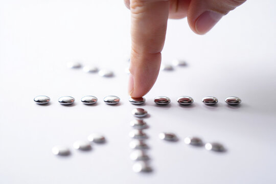 Person's Finger Gently Touching Silver Sphere among Array on Clean White Surface Creating Pattern for Modern Design 147 Characters