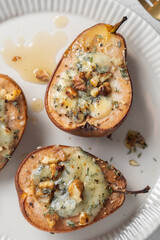Delicious baked pears stuffed with cheese and walnuts served on a white plate for a delightful dessert experience