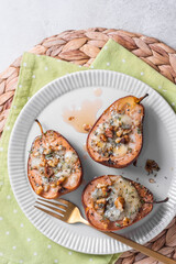 Delicious baked pears stuffed with cheese and walnuts served on a white plate for a delightful dessert experience