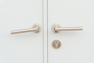 Obraz premium White door panel or door leaf with two silver door grips or handles and separated keyhole used as background