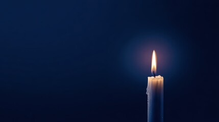 A single candle burning brightly against a dark blue background