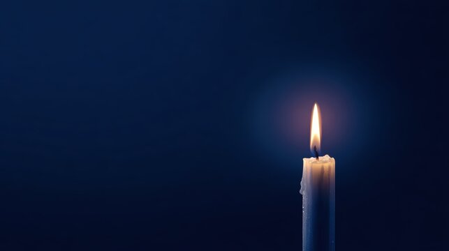 A single candle burning brightly against a dark blue background