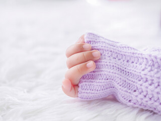 Close up of newborn baby hand is wearing a purple clothes on white bed
