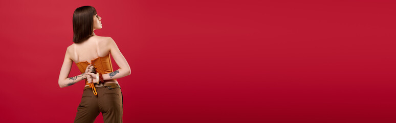 Stylish young woman poses elegantly against a vibrant red background expressing confidence and style