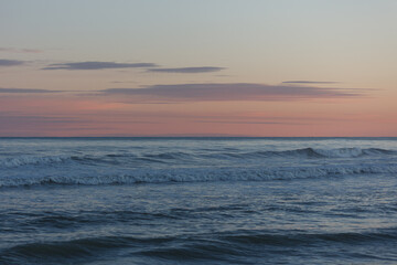 Obraz premium Soft evening waves under a pastel pink and blue sunset sky on the Mediterranean coast. Calm ocean background with gentle motion and dreamy colours.