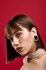 Stylish woman showcases elegance against a vibrant red backdrop