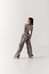 Fototapeta premium Young woman showcases unique style in trendy outfit with a confident pose