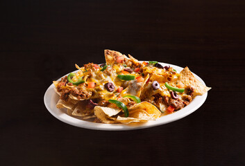 Nacho supreme platter with ground beef and vegetables covered in melted cheese and olives in a white dish; copy space