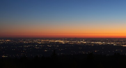 Fototapeta premium Illuminated cityscape spreads across the horizon under a dramatic twilight sky
