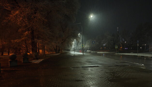 Novokuznetsk, Russia. November 01, 2024. A picturesque view of the trees of the city park covered with the first autumn snow and illuminated by lanterns of warm and cold light.