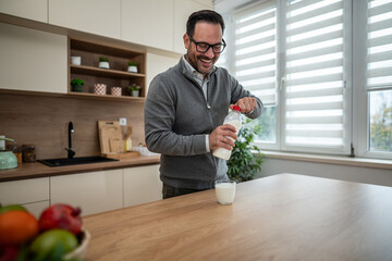 Happy man opening milk bottle in kitchen for breakfast